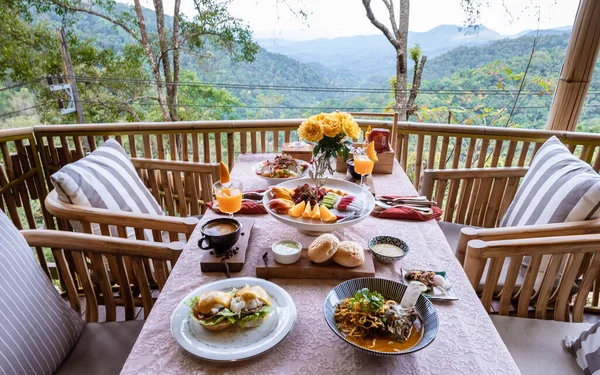 top view of a luxury breakfast in the mountains of Chiang Mai Thailand, luxury breakfast with Chiang Mai curry noodle soup or Khao Soi Gai and fruits and coffee on the table.