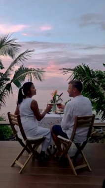Couple of men and women having a Romantic dinner on the beach of Koh Mak in Thailand during the sunset