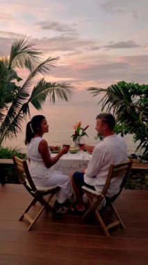 Couple of men and women having a Romantic dinner on the beach of Koh Mak in Thailand during the sunset