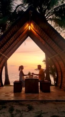 Couple of men and women having a Romantic dinner on the beach of Koh Mak in Thailand during the sunset