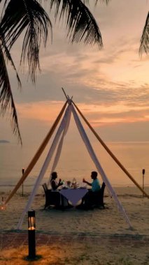 Couple having a Romantic dinner on the beach of Koh Chang in Thailand during sunset, Romantic dinner on the beach in Thailand during sunset