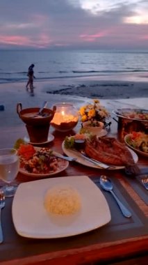 Asian Thai women having a Romantic dinner on the beach in Thailand during sunset.
