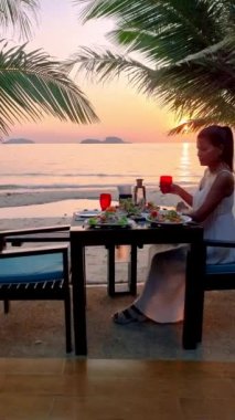 Asian Thai women having a Romantic dinner on the beach in Thailand during sunset.