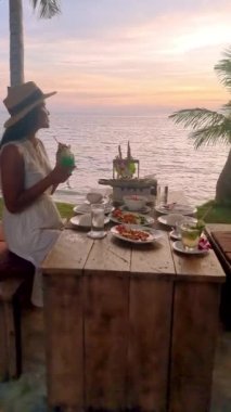 Asian Thai women having a Romantic dinner on the beach of Koh Mak in Thailand during sunset.