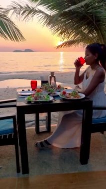Asian Thai women having a Romantic dinner on the beach of Koh Chang in Thailand during sunset