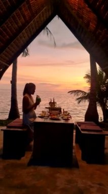 Asian Thai women having a Romantic dinner on the beach in Thailand during sunset.
