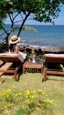 Asian women drinking wine at the oceanfront with a look over the tropical sea of Koh mak Thailand. 
