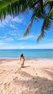 couple on a tropical beach during vacation at the Island of Koh Kood in Thailand, men and women on a white beach with palm trees. 