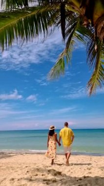 couple on a tropical beach during vacation at the Island of Koh Kood in Thailand, men and women on a white beach with palm trees on a sunny day
