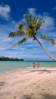 couple on a tropical beach during vacation at the Island of Koh Kood in Thailand, men and women on a white beach 