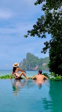 Couple at an infinity pool in Koh Phi Phi Thailand, men and women relaxing at the pool.