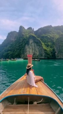 Asian women in front of a Longtail boats and green blue turqouse lagoon at Pileh Lagoon Tropical Island of Koh Phi Phi Thailand