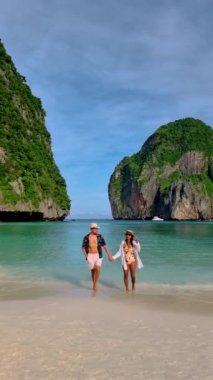 Couple of men and women with a hat walking at the beach of Maya bay at the Tropical Island of Koh Phi Phi Thailand, a couple on vacation in Thailand