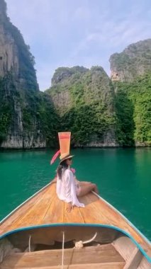 Asian women in front of a Longtail boats and green blue turqouse lagoon at Pileh Lagoon Tropical Island of Koh Phi Phi Thailand