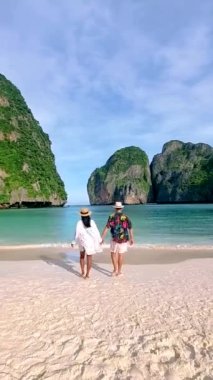 Couple of men and women with a hat walking at the beach of Maya bay at the Tropical Island of Koh Phi Phi Thailand, a couple on vacation in Thailand