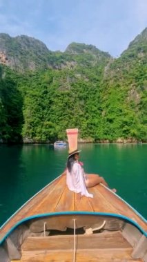 Asian women in front of a Longtail boats and green blue turqouse lagoon at Pileh Lagoon Tropical Island of Koh Phi Phi Thailand