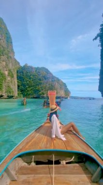 Asian women in front of a Longtail boats and green blue turqouse lagoon at Pileh Lagoon Tropical Island of Koh Phi Phi Thailand