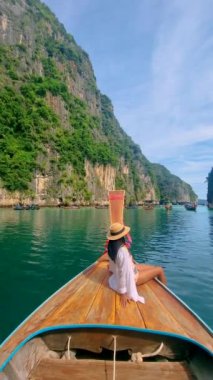Asian women in front of a Longtail boats and green blue turqouse lagoon at Pileh Lagoon Tropical Island of Koh Phi Phi Thailand