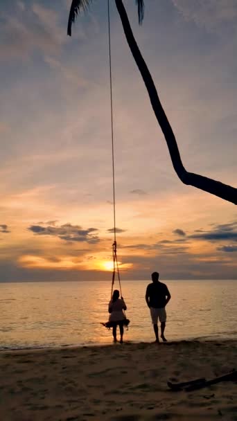 タイの日没の間 コッドのビーチでのスイングで男女のカップル — ストック動画