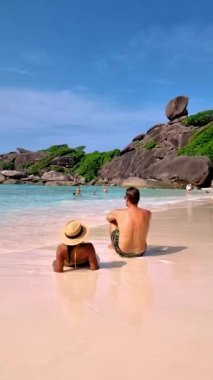 A couple of European men and Asian women relaxing on the beach of the Tropical Island Similan in Southern Thailand. 