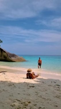 Couple of white men and Asian women relaxing on the beach of the Tropical Island Similan in Southern Thailand. 