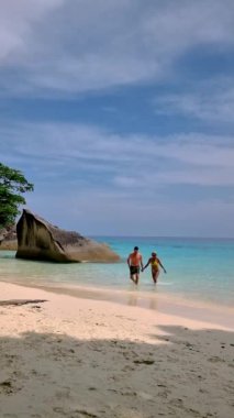 Couple of white men and Asian women relaxing on the beach of the Tropical Island Similan in Southern Thailand. 