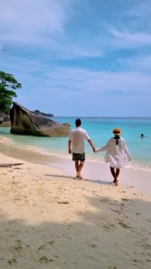 A couple of European men and Asian women relaxing on the beach of the Tropical Island Similan in Southern Thailand. 