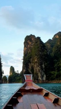 Asian women in front of a longtail boat at Khao Sok national park Thailand with limestone cliffs. 
