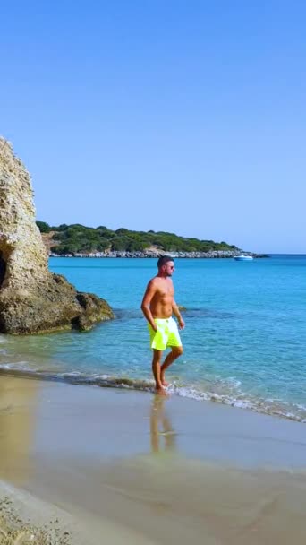 Voulismaビーチ Istron クレタ島 ギリシャ クレタ島の最も美しいビーチのビーチを歩いてショートパンツを泳ぐ若い男性 Agios Nikolaos近くのイストロン湾 — ストック動画