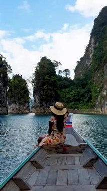 Asian women in front of a longtail boat at Khao Sok national park Thailand with limestone cliffs. 
