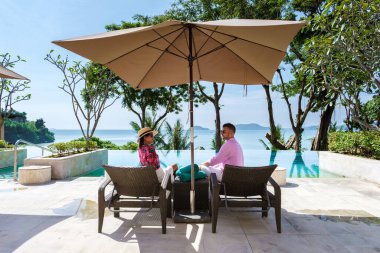 Tayland 'da lüks bir plaj sandalyesinde, orta yaşlı bir çift, erkekler ve Asyalı bir kadın havuzda güneşin batışını izliyorlar. Okyanusun üzerinde sonsuzluk havuzu