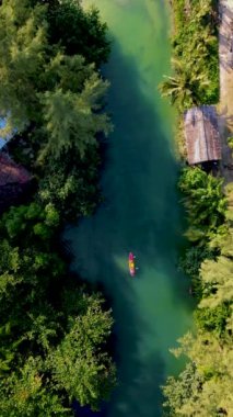 a couple of men and women in a kayak in the lagoon rainforest of Koh Chang Island Thailand.