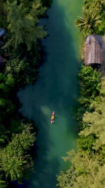 a couple of men and women in a kayak in the lagoon rainforest of Koh Chang Island Thailand.