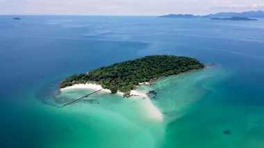 Tropical Island in Thailand with palm trees and black stones in the ocean of Koh Kham near Koh Mak. 
