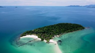 Tropical Island in Thailand with palm trees and black stones in the ocean of Koh Kham near Koh Mak. 