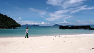 Asian women walking at a Tropical beach in Thailand with palm trees and black stones Koh Kham near Koh Mak
