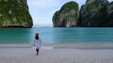 Asian Thai women walking at the beach with limestone cliffs at Koh Phi Phi Maya Bay Thailand. Women with a hat walking at the beach