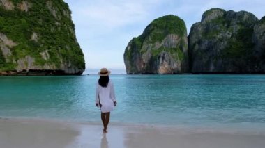 Asian Thai women walking at the beach with limestone cliffs at Koh Phi Phi Maya Bay Thailand. 