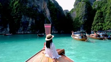 Asian women in front of a longtail boat at Koh Phi Phi Island Thailand, Pileh Lagoon.