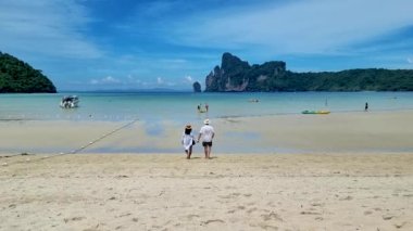 couple at a tropical white beach with limestone cliffs of Koh Phi Phi Thailand, men and women walking at the beach