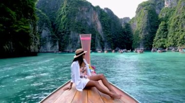 Asian women in front of a longtail boat at Koh Phi Phi Island Thailand, Pileh Lagoon.
