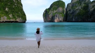 Asian Thai women walking at the beach with limestone cliffs at Koh Phi Phi Maya Bay Thailand. 