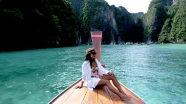 Asian women in front of a longtail boat at Koh Phi Phi Island Thailand, Pileh Lagoon.