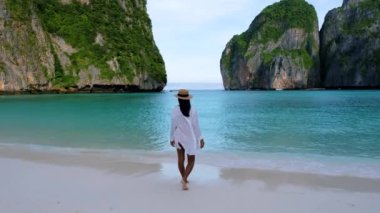 Asian Thai women walking at the beach with limestone cliffs at Koh Phi Phi Maya Bay Thailand. Women with a hat walking at the beach