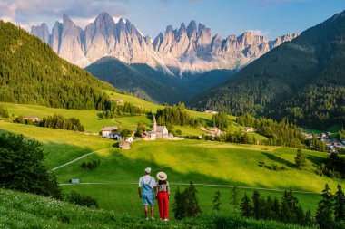 couple viewing the landscape of Santa Maddalena Village in Dolomites Italy, Santa Magdalena village magical Dolomites mountains, Val di Funes valley, Trentino Alto Adige region, South Tyrol, Italy,  clipart
