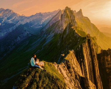 Couple watching the sunset at the Ridge of the majestic Schaefler peak in the Alpstein mountain range Appenzell, Switzerland Berggasthaus Schafler