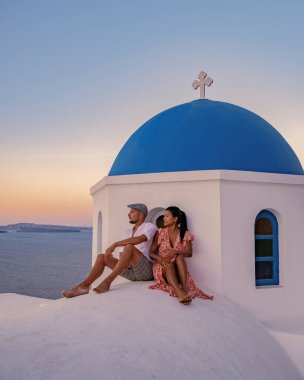 Yunanistan 'ın Oia Santorini köyünde tatil yapan orta yaşlı ve Asyalı genç bir çift olan Santorini Yunanistan, lüks tatil Santorini. Orta yaşlı erkek ve kadın, Santorini 'nin günbatımını izliyor.