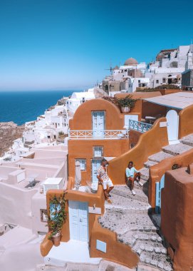 Yunanistan 'ın Oia Santorini köyünde tatil yapan orta yaşlı ve Asyalı genç bir çift olan Santorini Yunanistan, lüks tatil Santorini. Orta yaşlı erkek ve kadın, Santorini 'nin günbatımını izliyor.