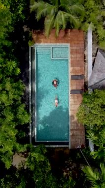 drone view from above a couple in a swimming pool in the rainforest jungle. 