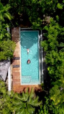 drone view from above a couple in a swimming pool in the rainforest jungle. 